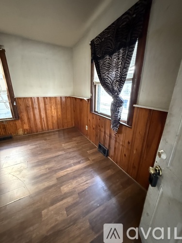A room with wooden walls and a window with a black lace curtain.