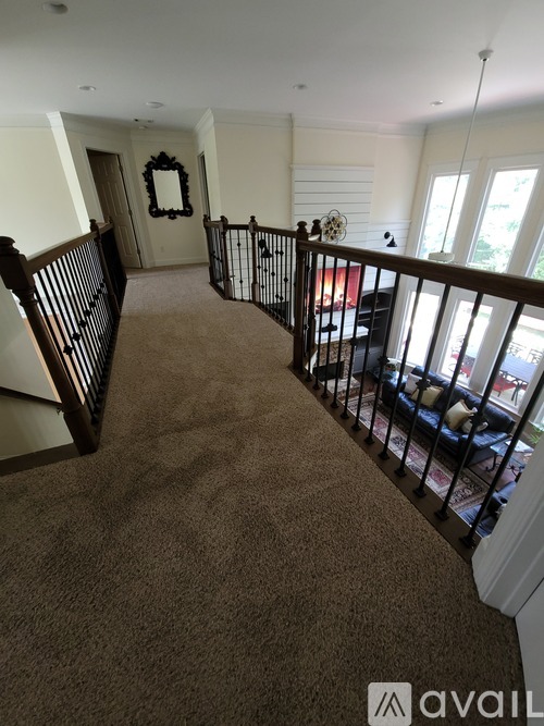 A carpeted staircase with a black railing and a mirror on the wall.