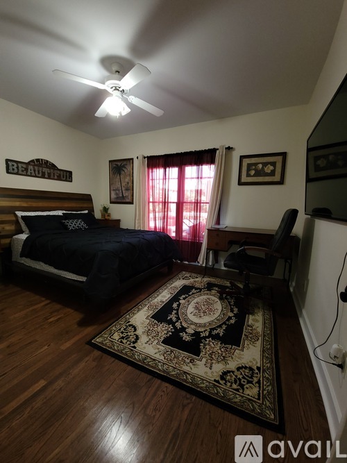 A bedroom with a bed, chair, and rug.