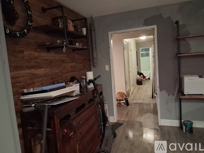A room with a wooden wall and a cat sitting on the floor.