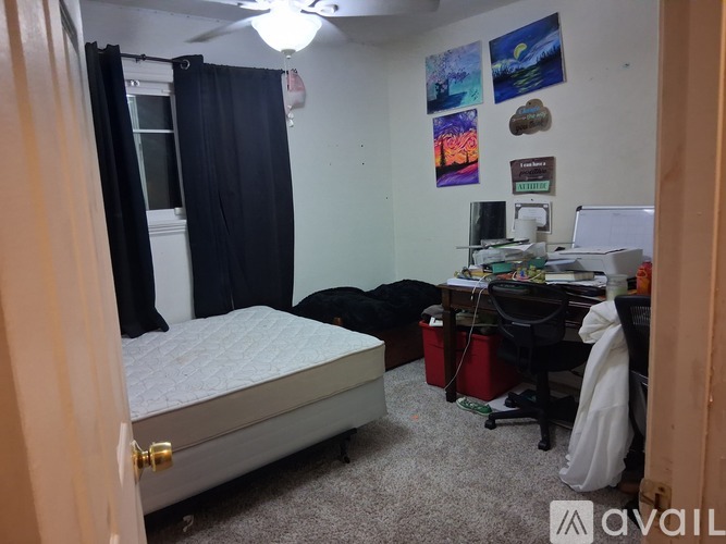 A room with a bed, desk, and a fan.