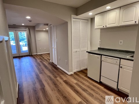 A kitchen with white cabinets and a wooden floor.