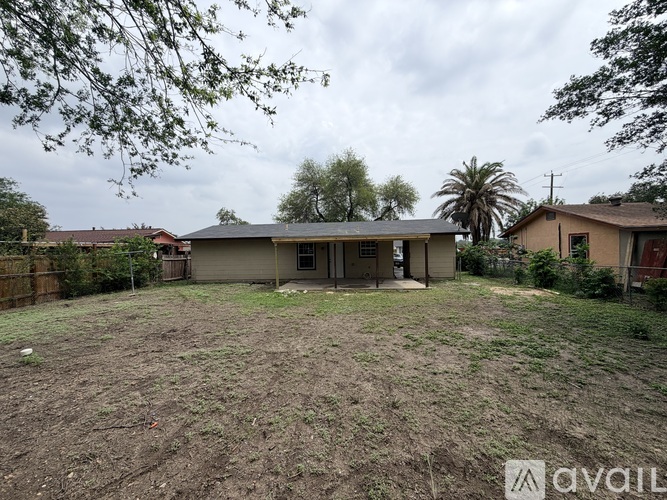 A backyard with a house, trees, and a fence.