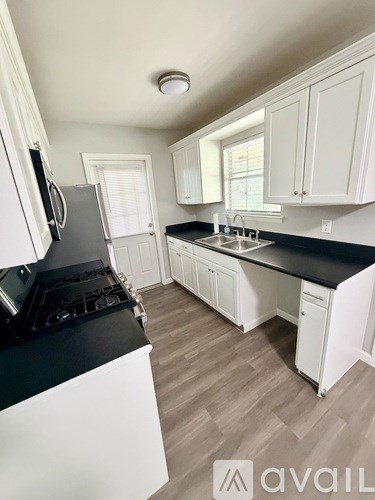 A kitchen with white cabinets and a black countertop.