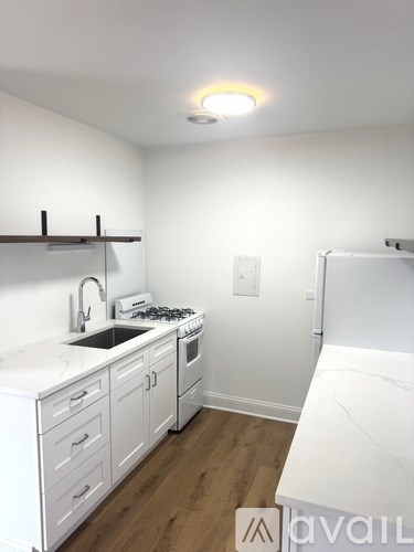 A kitchen with white cabinets and a wooden shelf.
