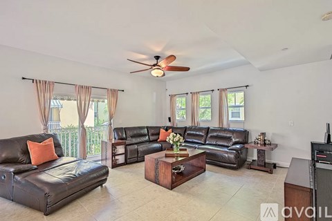 A living room with a black leather couch and a wooden coffee table.