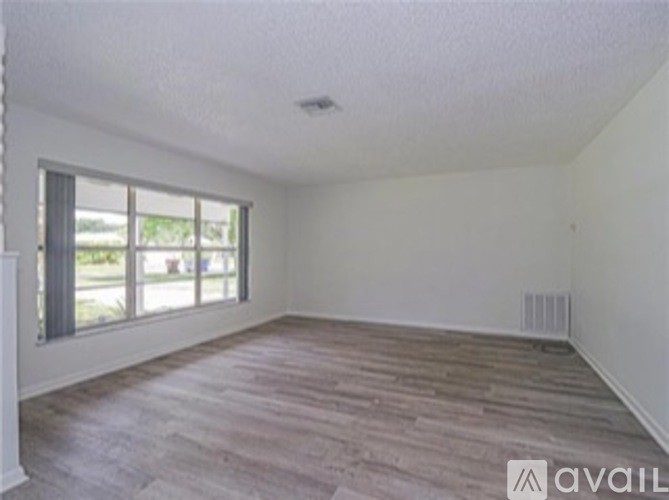 Empty room with wooden floor and large window.