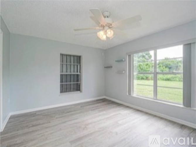A room with a ceiling fan and a window with bars.