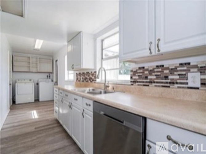 A kitchen with white cabinets and a wooden counter.