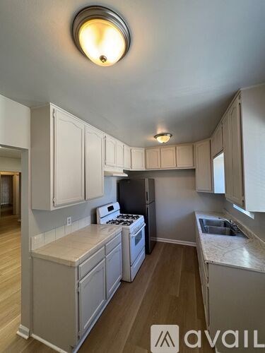 A kitchen with white cabinets and a stove top oven.