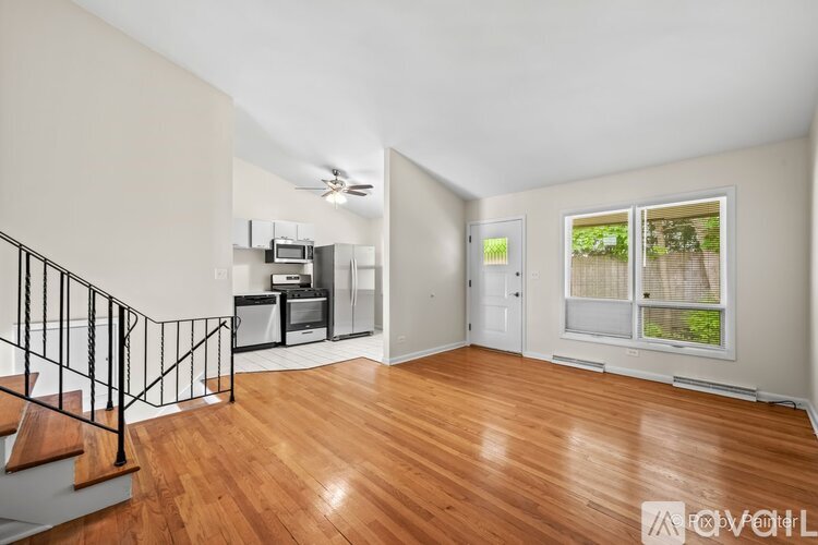 A living room with a staircase and a kitchen area.