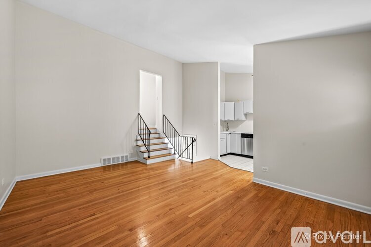 A room with wooden floors and a staircase leading to another room.