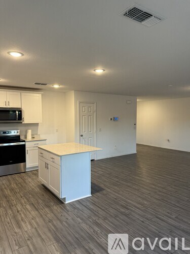 A kitchen with white cabinets and a wooden floor.