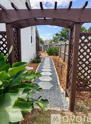 A garden pathway is framed by a lattice fence and a wooden archway.