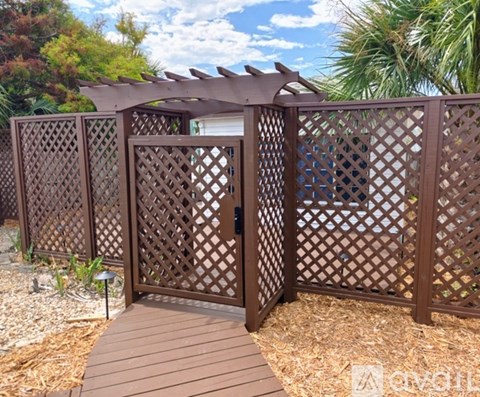 A brown lattice fence with a wooden walkway leading to a gate.