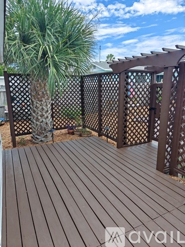 A wooden deck with lattice fencing and a palm tree.