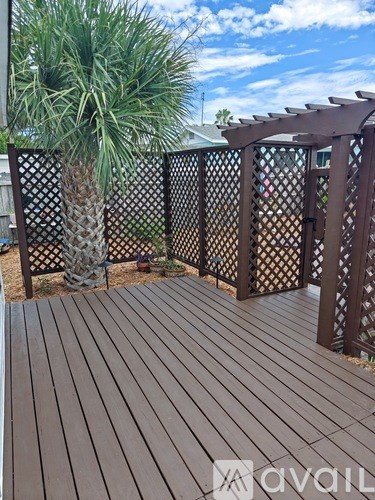 A wooden deck with lattice fencing and a palm tree.