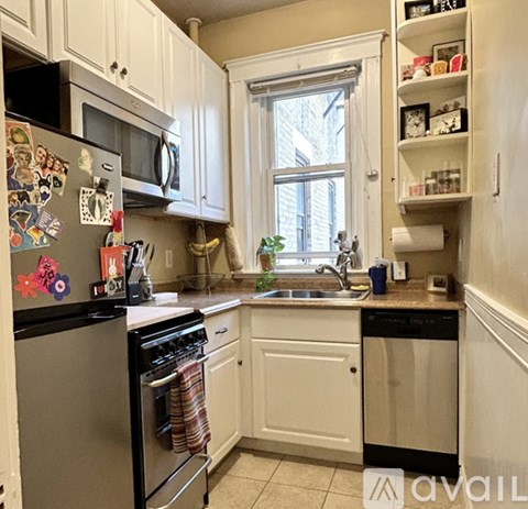 A kitchen with white cabinets and a black fridge.