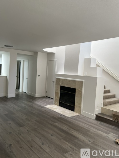 A living room with a fireplace and a staircase.