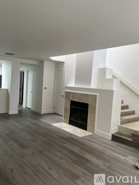 A living room with a fireplace and a staircase.