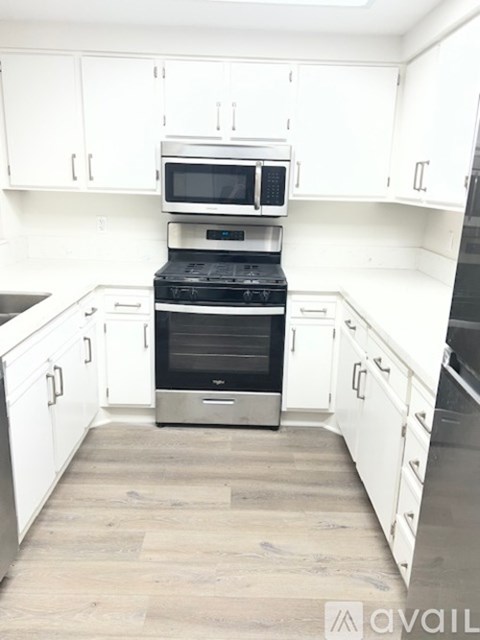 A kitchen with white cabinets and a stove top oven.