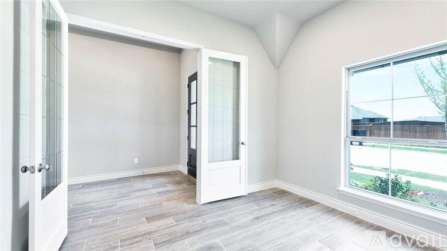 A room with a door and a window showing a view of a fence and trees.
