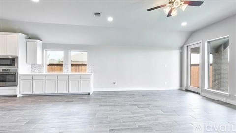 A spacious kitchen with white cabinets and a ceiling fan.