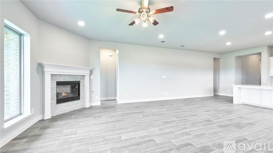 A spacious living room with a fireplace and a ceiling fan.