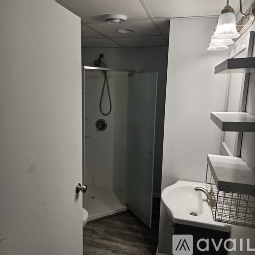 A bathroom with a sink, mirror, and shower.