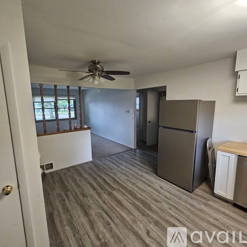 A room with a ceiling fan and a refrigerator.