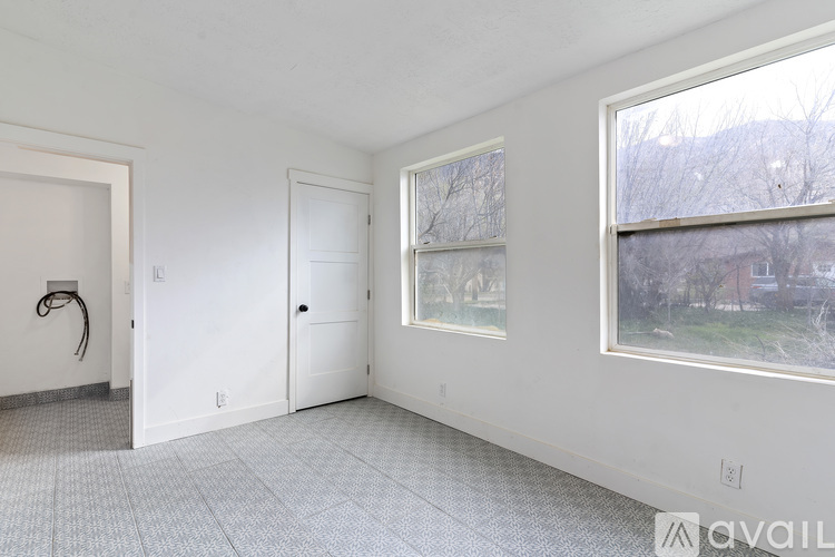 A room with a large window, a door, and a wall-mounted light fixture.