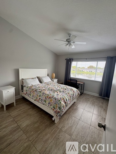 A bedroom with a floral bedspread and a white bed frame.