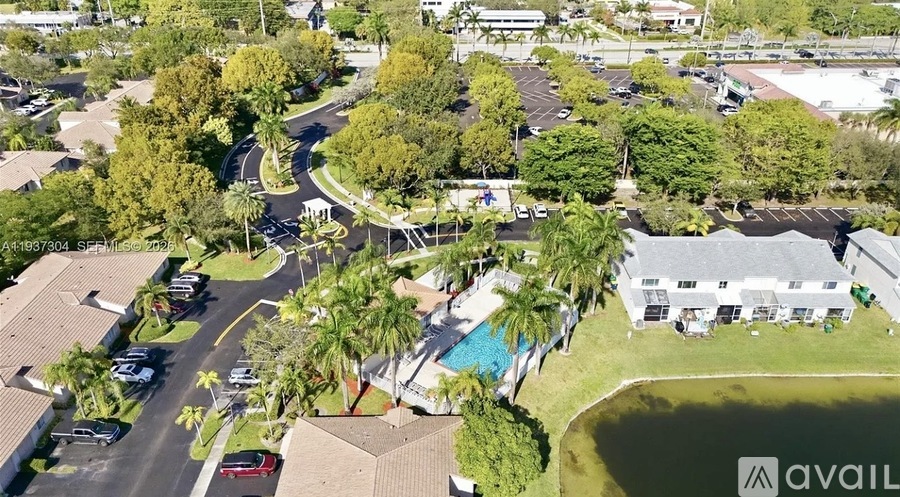 A bird's eye view of a residential area with houses, cars, and a pool.