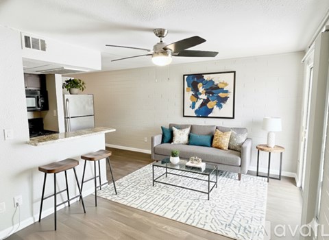 A living room with a grey couch, a coffee table, and a painting on the wall.