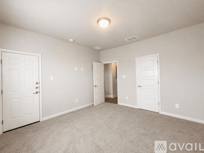 A spacious room with white doors and carpeted floor.