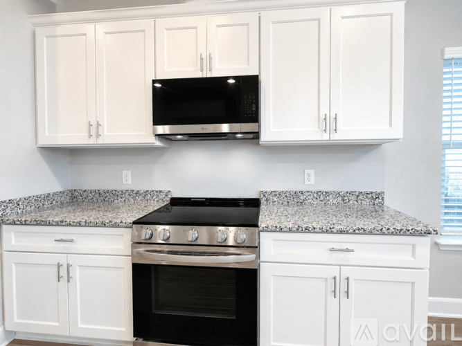 A kitchen with white cabinets and a black stove top oven.