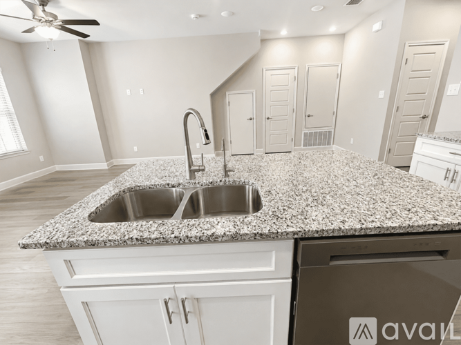 A kitchen with a granite countertop and a stainless steel sink.