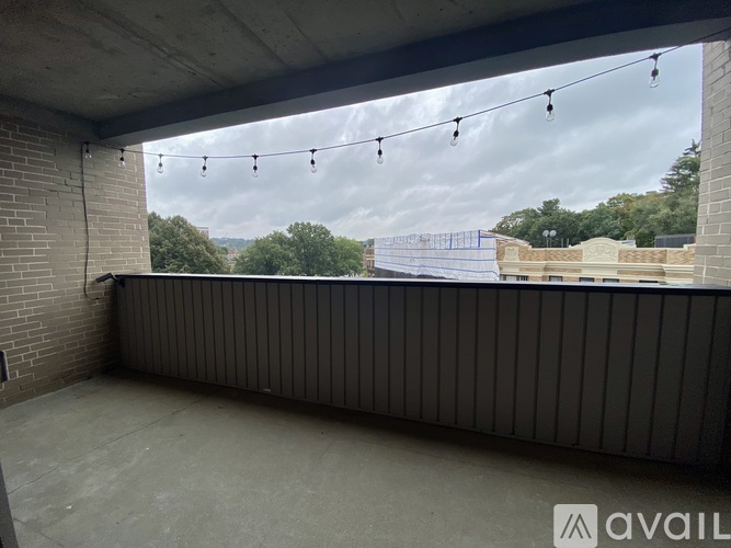 A balcony with string lights and a view of the sky and trees.