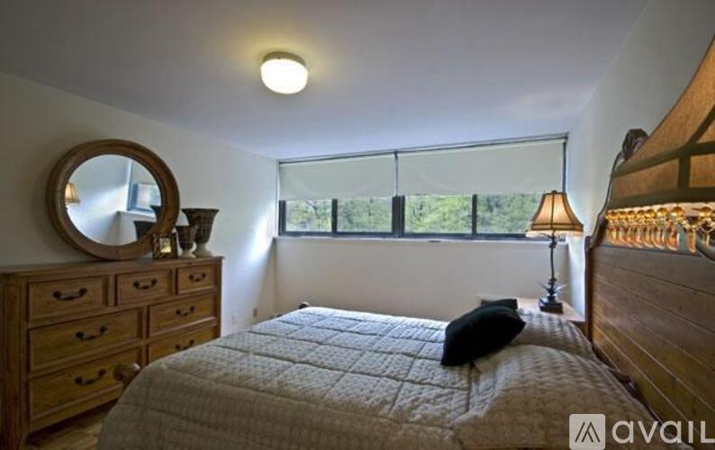 A bedroom with a bed, dresser, and window.