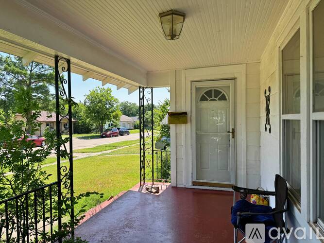 A porch with a white door and a red floor.