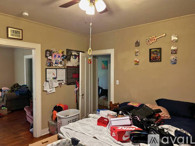 A bedroom with a bed in the center of the room with a lot of stuff on it.