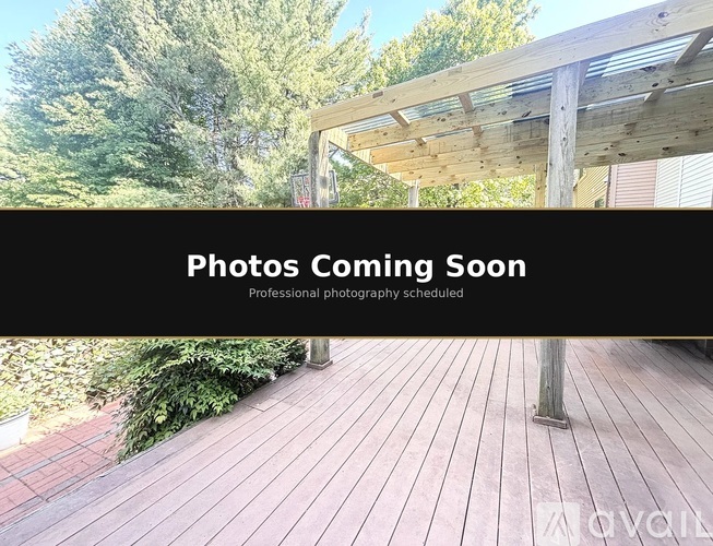 A wooden deck with a roof and trees in the background.