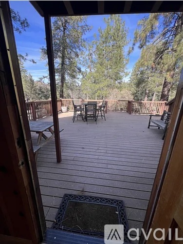 A wooden deck with a table and chairs overlooking a wooded area.