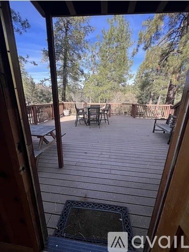 A wooden deck with a table and chairs overlooking a wooded area.