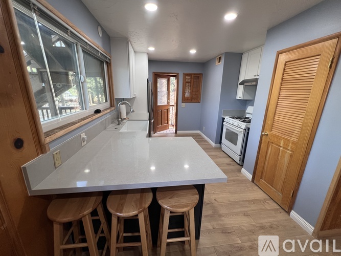 A kitchen with a large island and wooden stools.