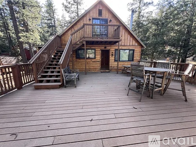 A wooden cabin with a deck and chairs.