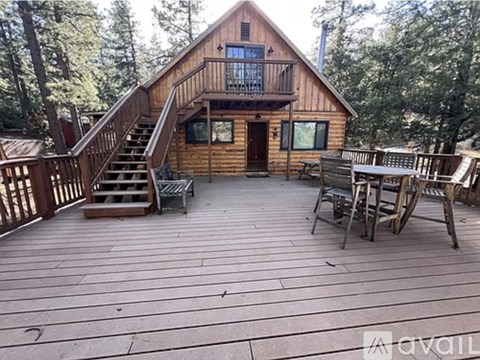 A wooden cabin with a deck and chairs.