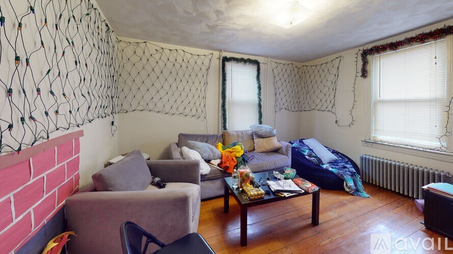 A living room with a grey couch, a brown coffee table, and a red brick wall.