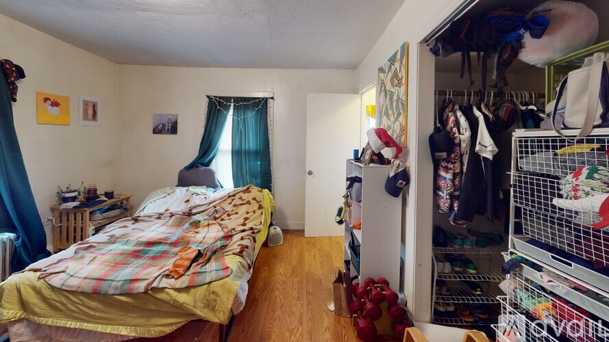 A bedroom with a bed and a closet full of clothes.
