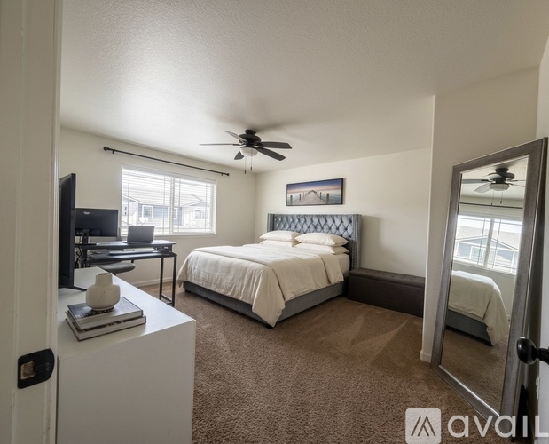 A bedroom with a bed, desk, and television.